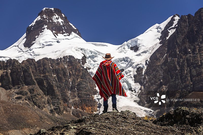 在玻利维亚安第斯山脉科迪勒拉山脉秃鹰峰背景下的雨披旅行者图片素材