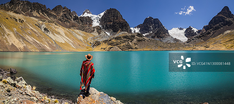 在玻利维亚安第斯山脉Condoriri峰和湖背景下的穿披风的旅行者图片素材