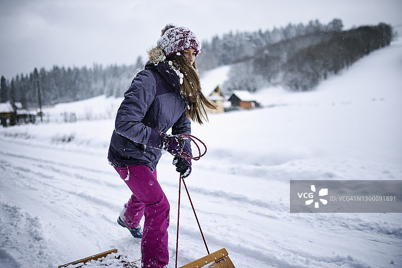 少女像玩滑板一样玩雪橇图片素材