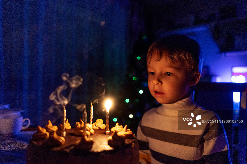 小男孩和带有四根蜡烛的蛋糕，庆祝生日图片素材