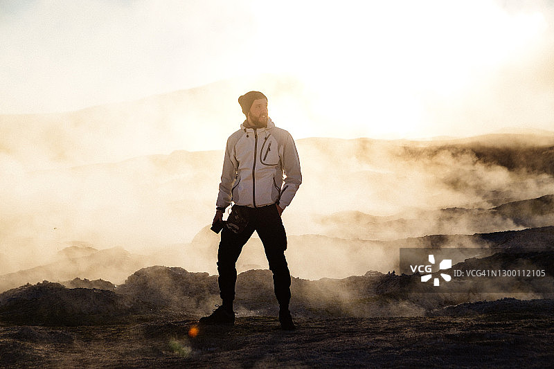 男人站在玻利维亚高原的马尼亚纳地热区前，欣赏日出图片素材