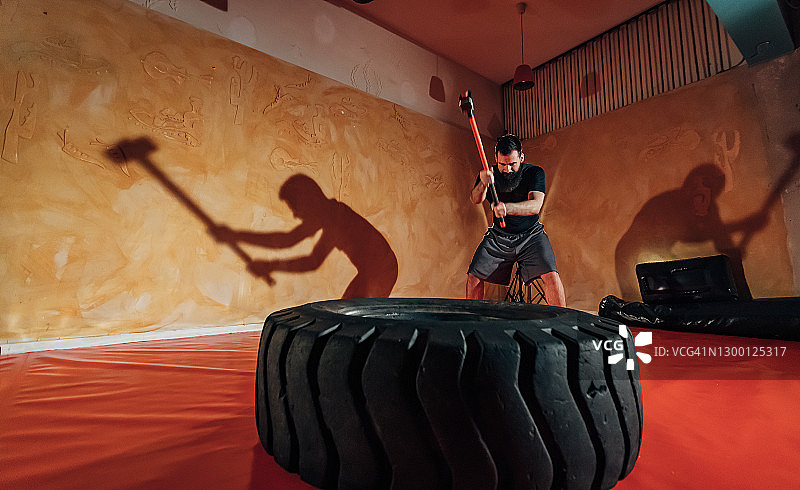 健壮的男人用大锤击打巨轮图片素材
