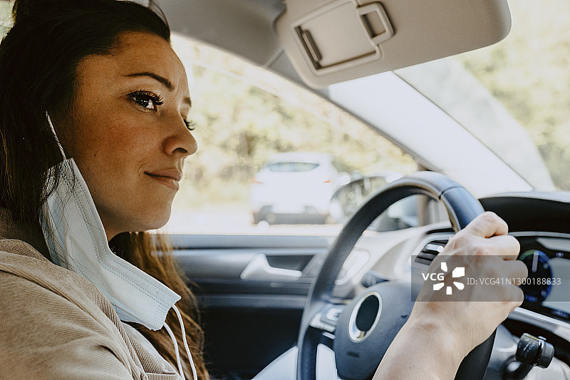 疫情期间，女子坐在电动汽车里向远处眺望图片素材