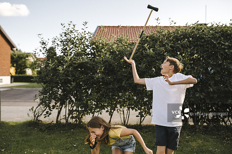哥哥在后院用妹妹平衡马球球槌图片素材