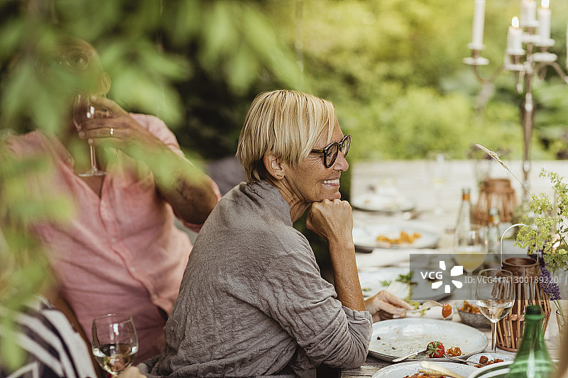 笑容满面的奶奶手托着下巴，坐在花园聚会中的父亲旁边图片素材