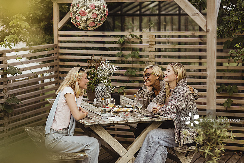 微笑的女性朋友和奶奶在前院的桌旁共度时光图片素材