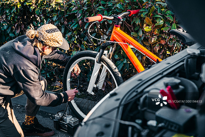 俄罗斯索契：一位年轻人用车载气泵给自行车轮胎打气图片素材
