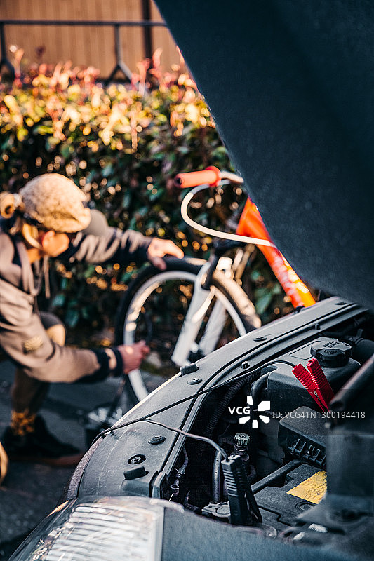 俄罗斯索契：一位年轻人用车载气泵给自行车轮胎打气图片素材