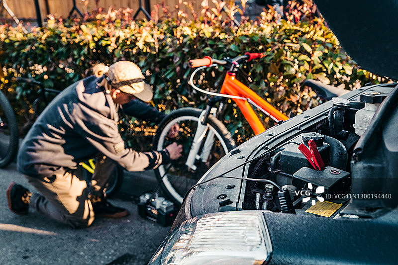 俄罗斯索契：一位年轻人用车载气泵给自行车轮胎打气图片素材