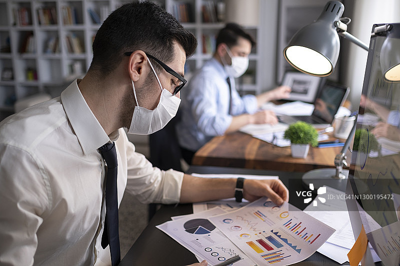 在办公室戴防护口罩工作的商务人士，COVID-19病毒图片素材