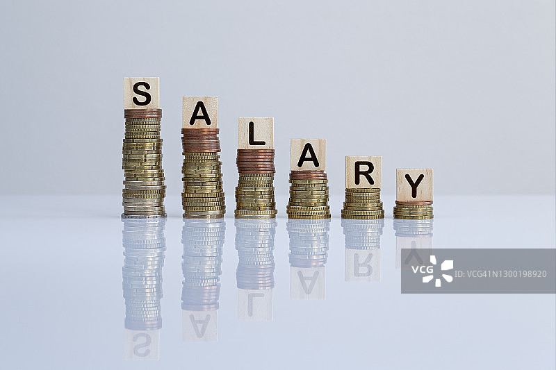 灰色背景下硬币堆上的“薪水”字样木块图片素材
