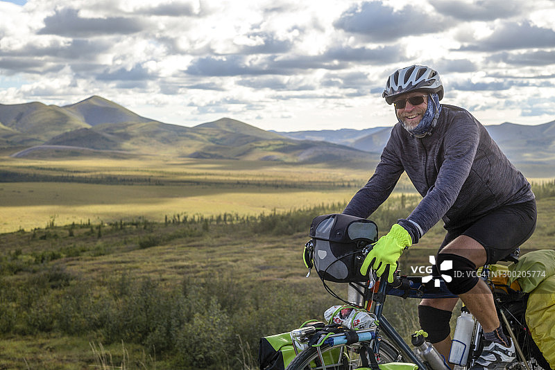 中年男人在山路上骑自行车并对着镜头微笑图片素材