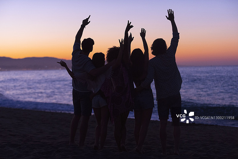 在日落或日出时在海滩上聚会的人群图片素材