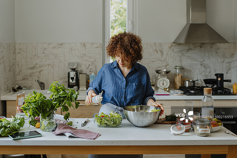 快乐的女人在厨房里拌沙拉（留白）图片素材