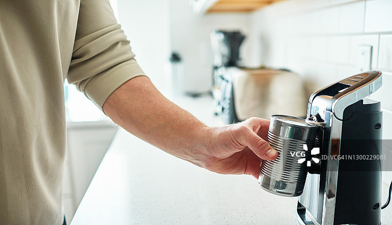 男子用电动开罐器打开一罐食物图片素材