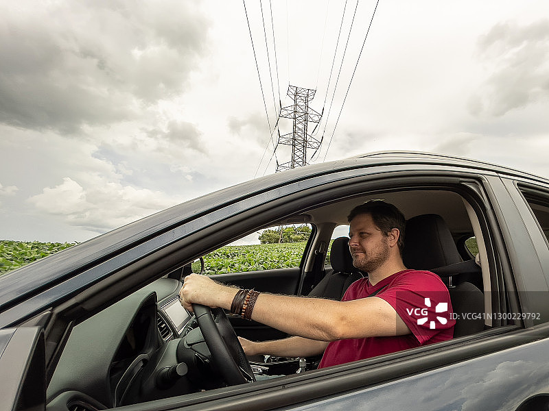 在乡村道路上驾车，背景是电线的男人图片素材
