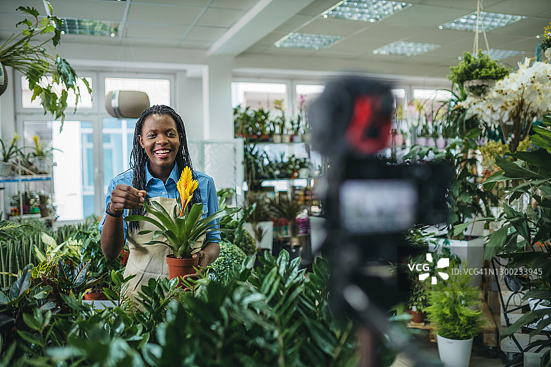 年轻女人在温室里拍摄视频博客图片素材