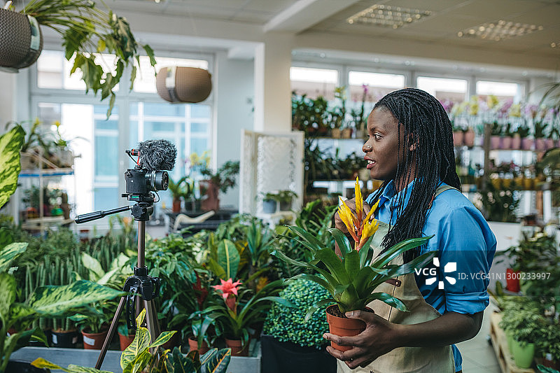 年轻女人在温室里拍摄视频博客图片素材