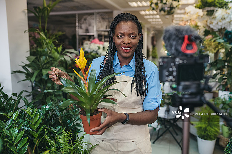 年轻女人在温室里拍摄视频博客图片素材