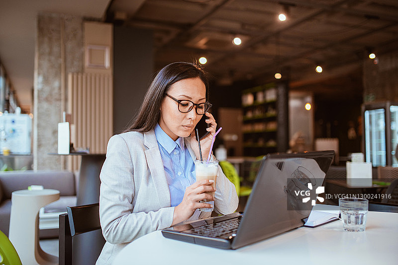 在咖啡店使用笔记本电脑工作的亚洲女人图片素材