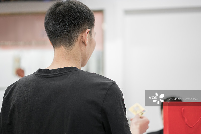 亚洲男人在收银台使用银行卡付款图片素材
