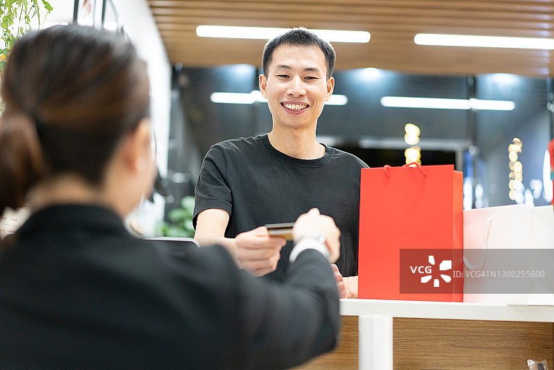亚洲男人在收银台使用银行卡付款图片素材