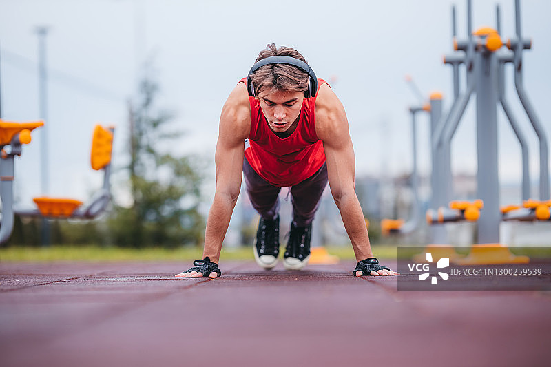 在户外做俯卧撑的年轻健壮男人图片素材
