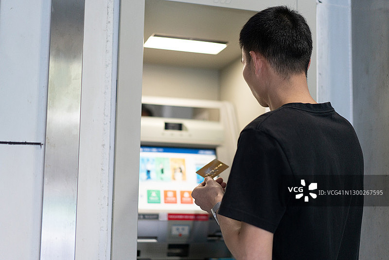 亚洲男人在自动取款机上取款图片素材