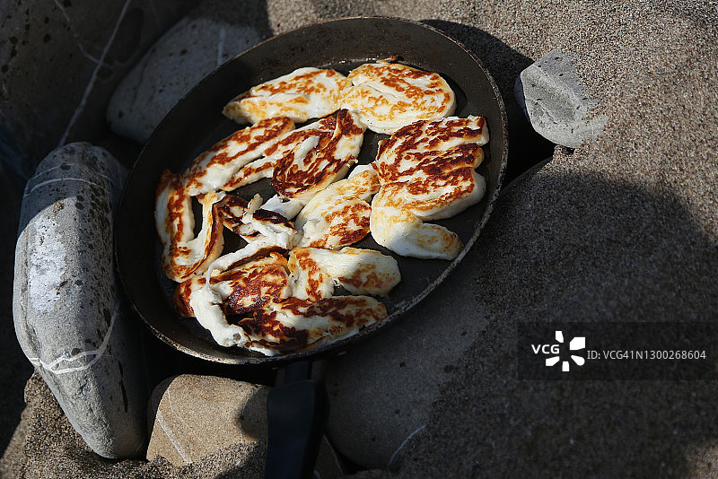 在海滩的热石上烤制的传统塞浦路斯哈罗米奶酪图片素材