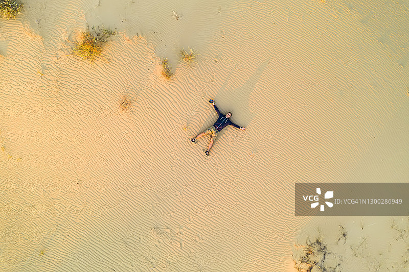 航拍视角：男人躺在沙漠的沙滩上图片素材