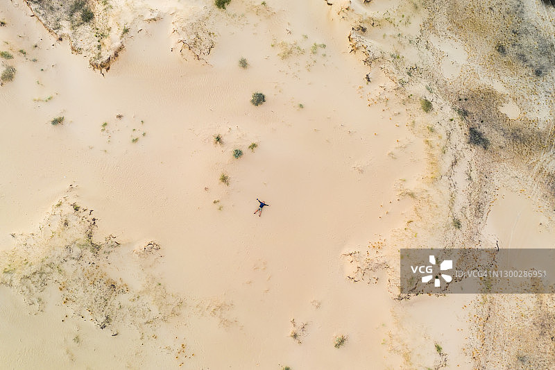 航拍视角：男人躺在沙漠的沙滩上图片素材