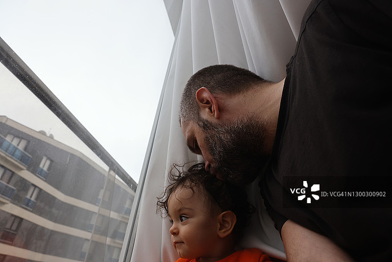 隔离期间，女婴和她的父亲正在看窗外图片素材