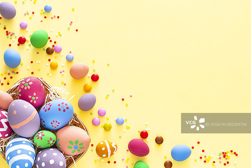 黄色背景上的彩色复活节彩蛋、糖果和糖屑，留有复制空间图片素材
