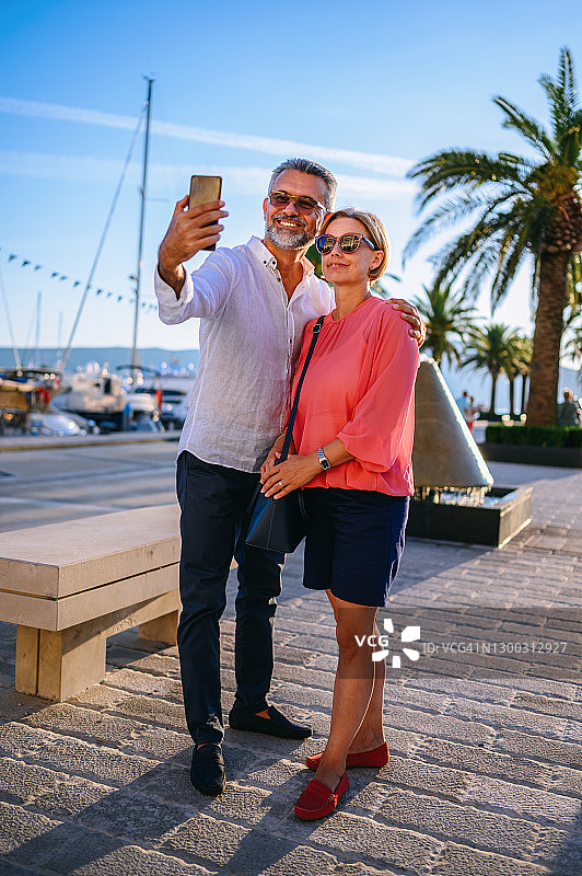 一对中年夫妇在港口用智能手机拍照图片素材