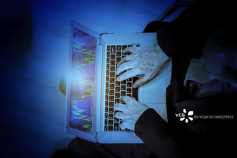 商务概念：深蓝色背景下商务人士用笔记本电脑查看股票趋势图片素材