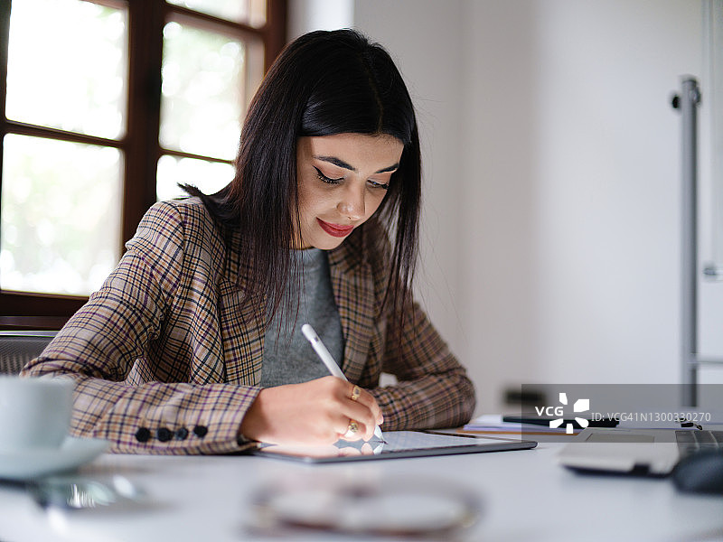 年轻女设计师在办公室用数位笔在数位板上绘图图片素材