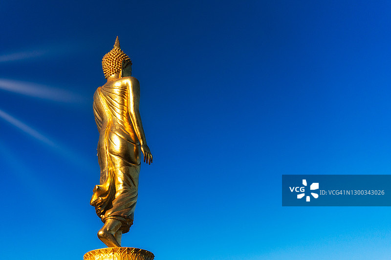 美丽的金色佛像，蓝天阳光，展现泰国传统风格的柔和线条，用作宗教背景图片素材
