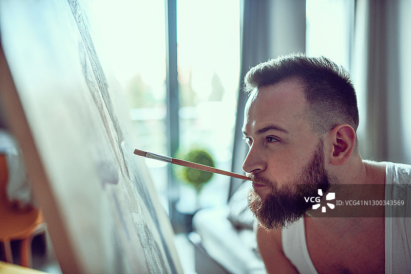 残疾男人用嘴衔着画笔绘画图片素材