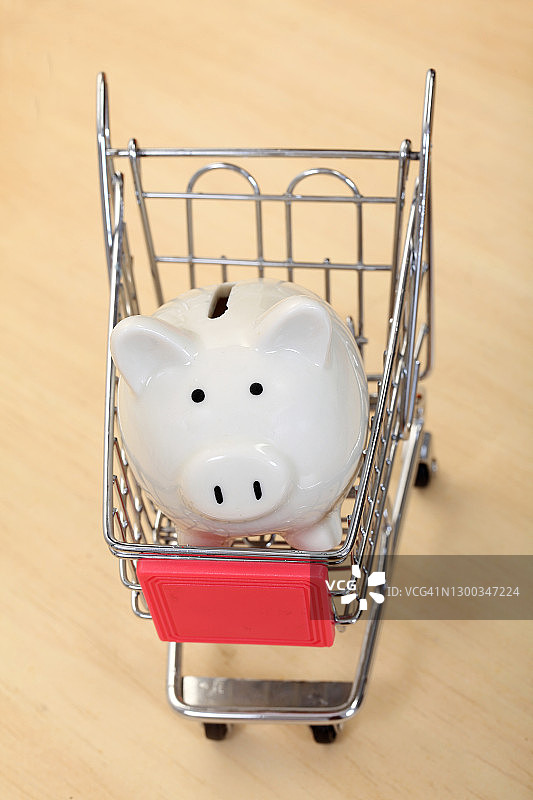 在小型购物车中的白色小猪储蓄罐图片素材