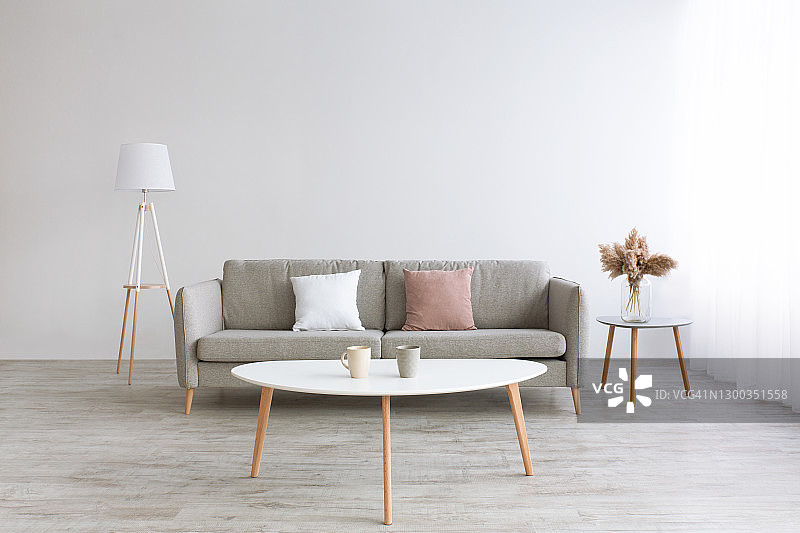 带有木地板和自然光的房间，灰色沙发配白色和粉色枕头图片素材