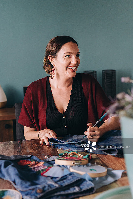 快乐女人在画布上绘制图案进行刺绣图片素材