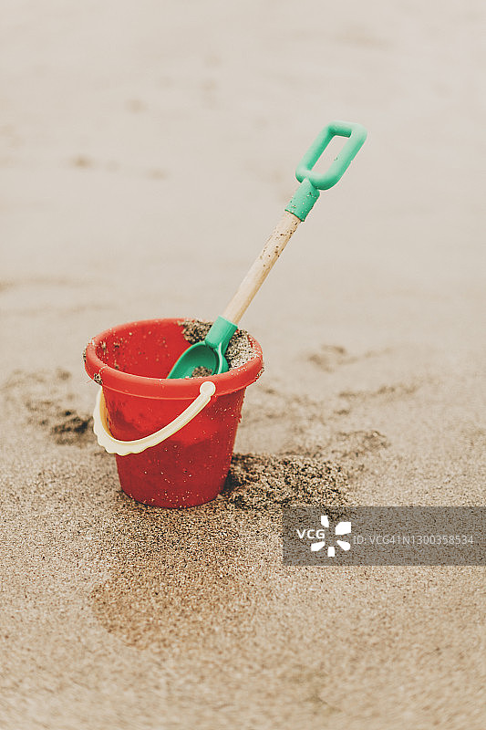 海滩上度假用的红色桶和绿色铲子玩具图片素材