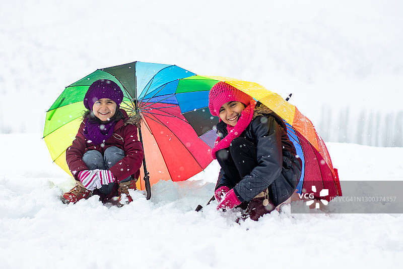 小女孩在雪中撑着彩色雨伞图片素材