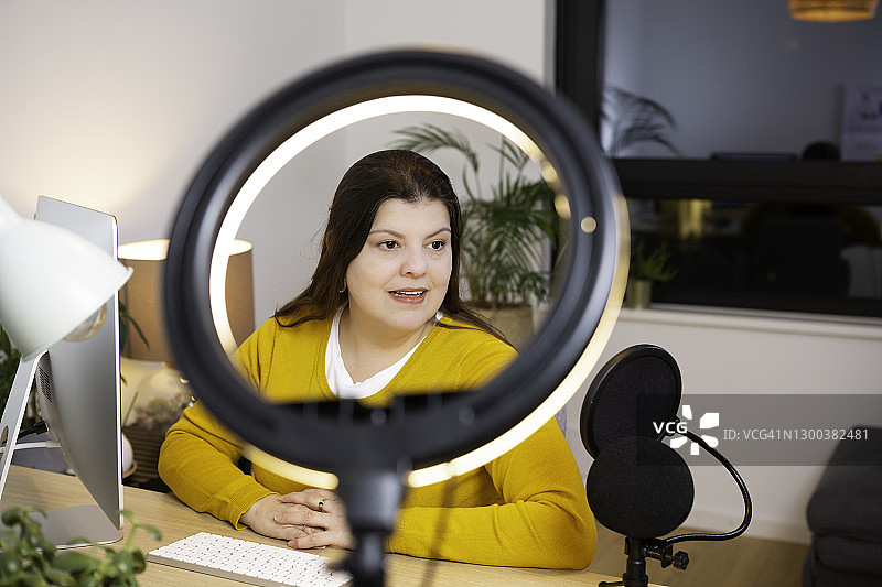 美女博主在家中办公室工作，对着麦克风讲话图片素材