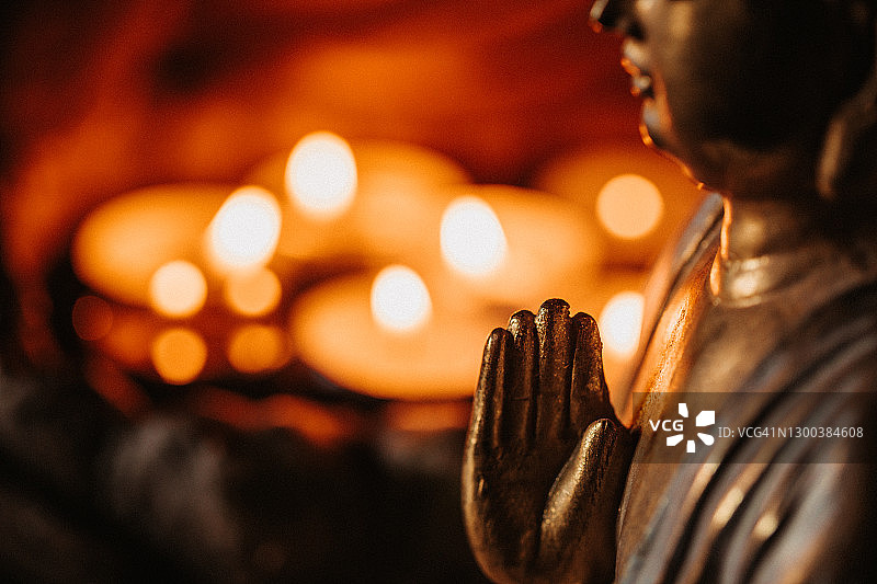 点燃的蜡烛前，佛像侧面特写图片素材