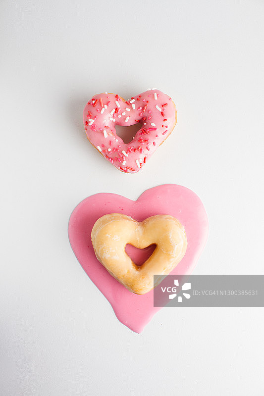 两个甜甜圈爱心，粉色糖霜在桌上图片素材