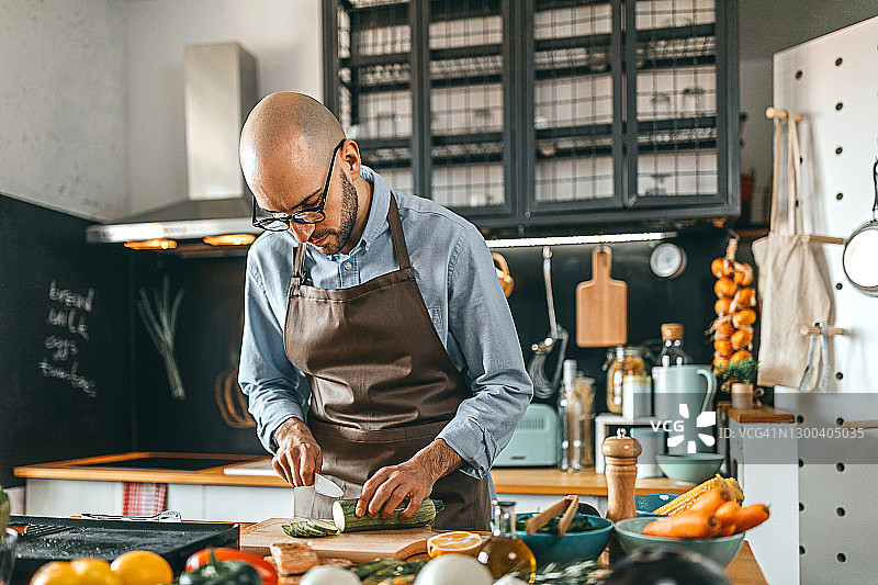 在砧板上切西葫芦的青年男子图片素材