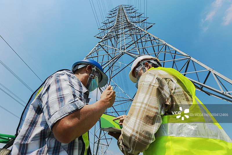 工程师与工人在建筑或电力工地背景下讨论工程行业图片素材