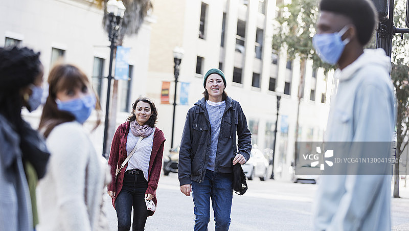 年轻夫妇在城市中与戴着口罩的朋友会面图片素材