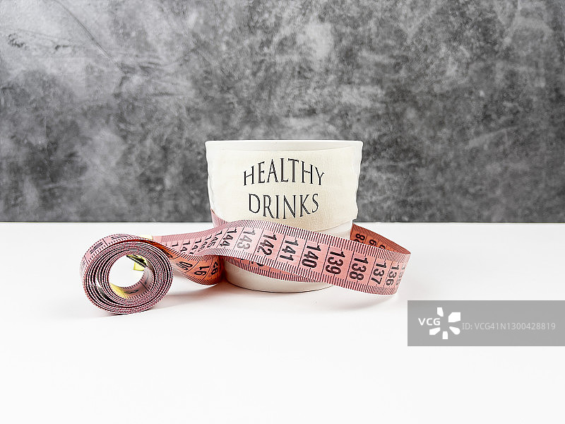 白色马克杯中的健康饮品与卷尺，健康概念背景图片素材